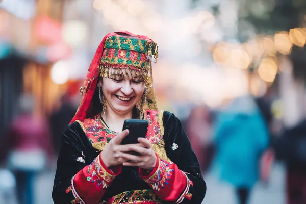 App 39D — Rápido, responsivo e otimizado para todos os dispositivos Uma mulher alegre em roupas tradicionais usando seu smartphone durante um momento festivo, mostrando como o app 39D se encaixa facilmente no dia a dia.